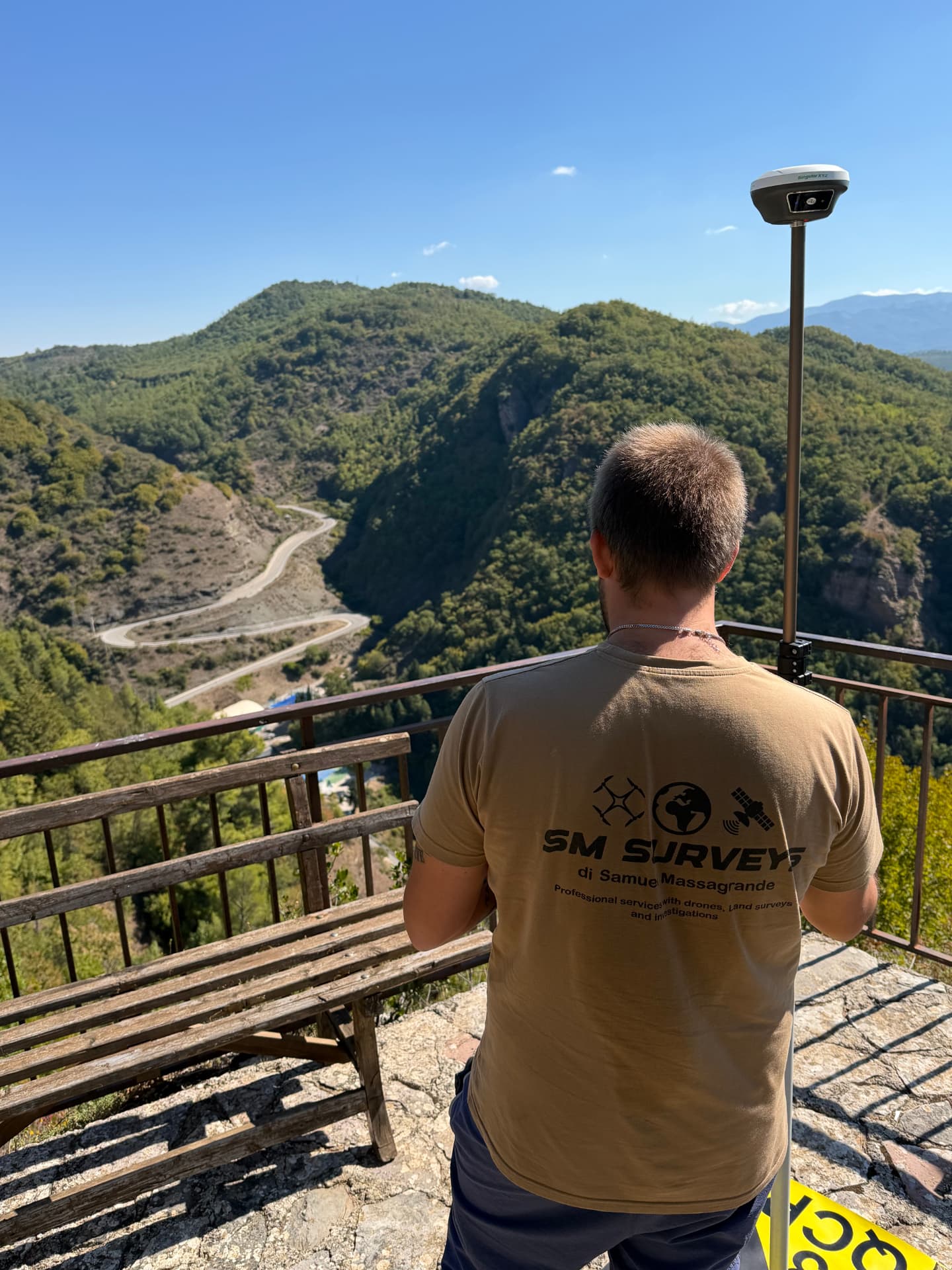 Topografo con ricevitore GNSS su pala in posizione panoramica